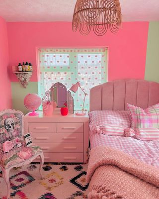 A pink bedroom with a pink bed, drawers, and chair
