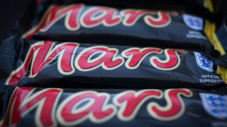 Three mars bars stacked on top of one another, each with their logos facing upwards towards the camera