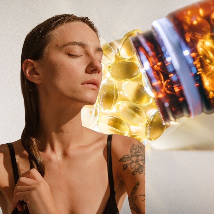 a woman with clear glowing skin with eyes closed overlaid on a bottle of gold pills spilled on a white surface