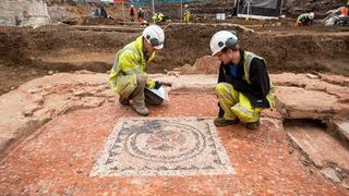 Archeologists kneel beside a Roman mosaic discovered in central London.