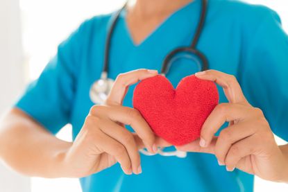 A nurse holds a red heart.