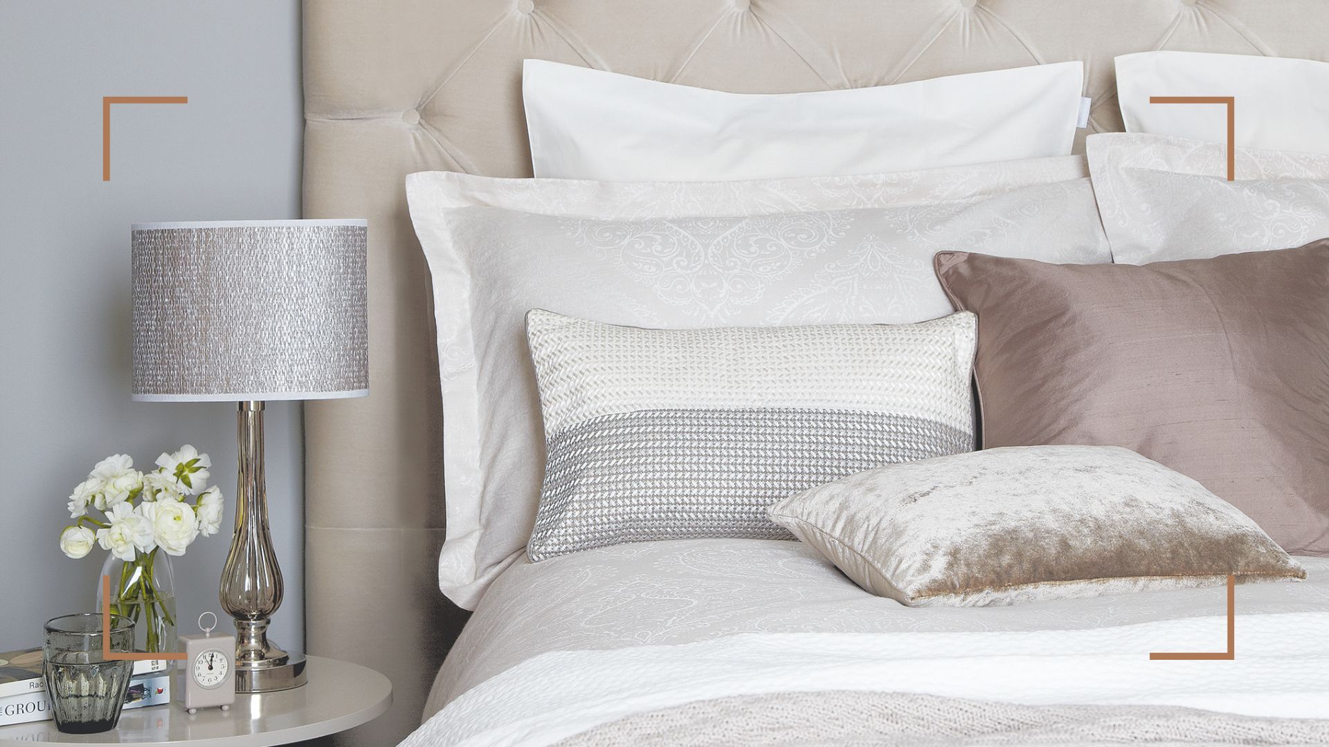 neutral bedroom with a beige upholstered bed with stacked pillows to explain the reason your pillows need cleaning more often