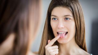 Woman examining her tongue in a mirror