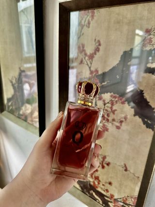 A bottle of Dolce & Gabbana Q Intense perfume in front of a picture of cherry blossoms.