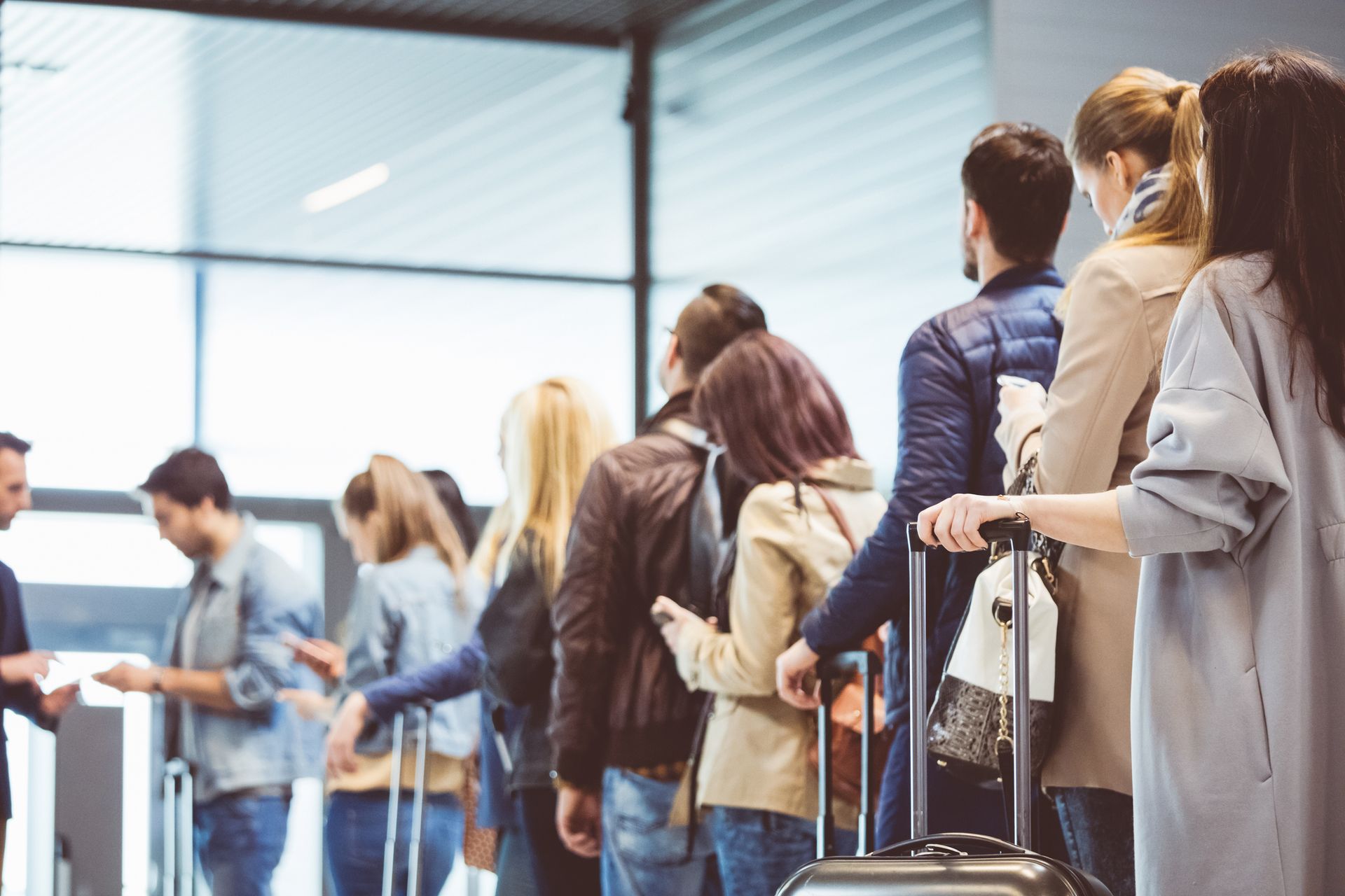 People with suitcases in line at the airport.