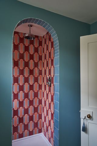 A tiled shower in a bright red color separates the space