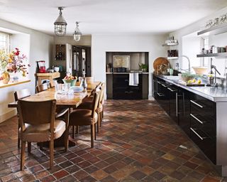 A kitchen with terracotta kitchen floor tile ideas and black modern high gloss cabinets