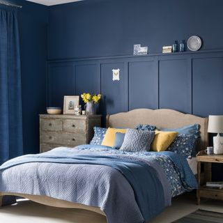 Navy blue bedroom with wall panels and wooden bed