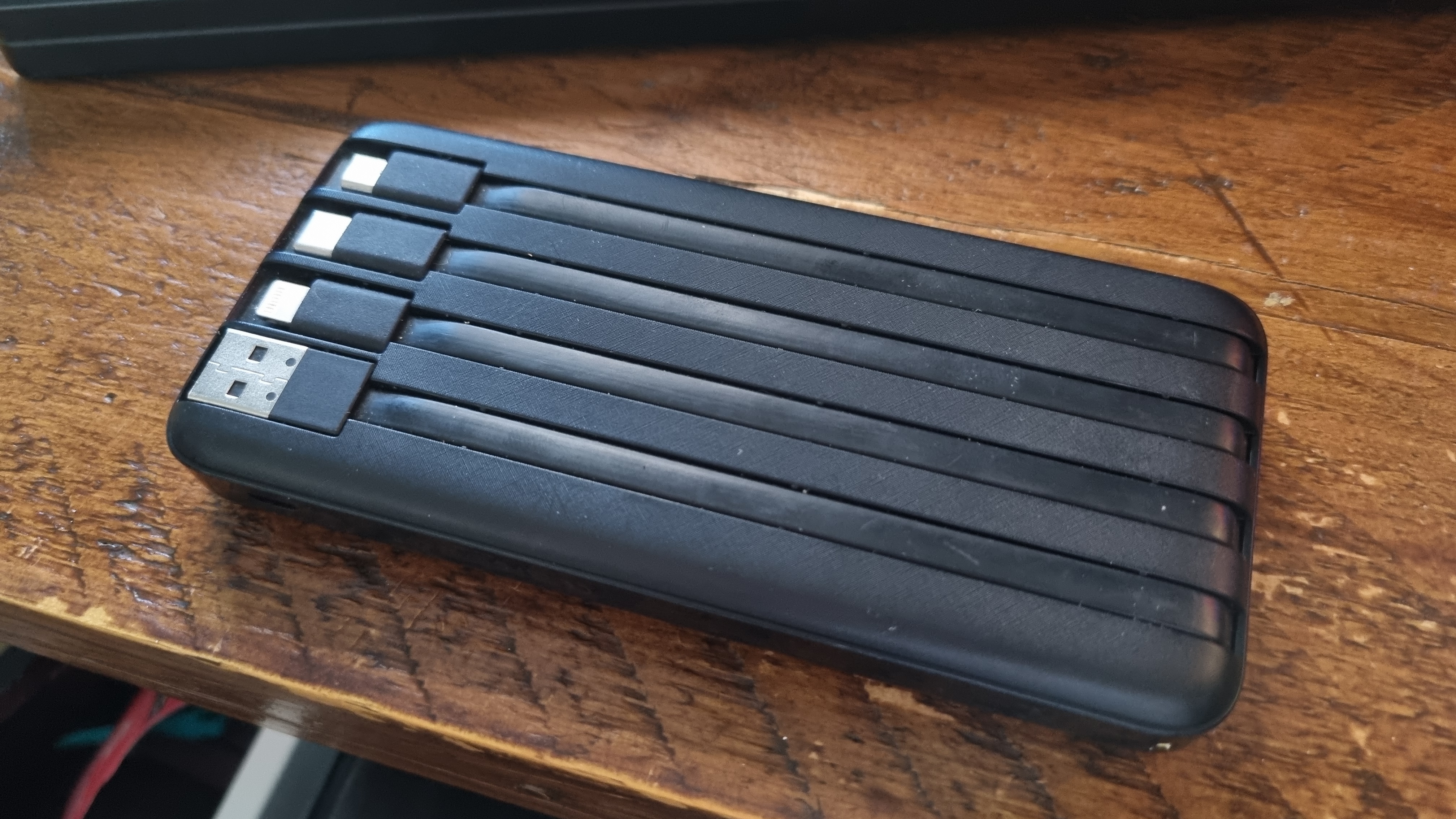 A Charmast portable power bank on a wooden desk