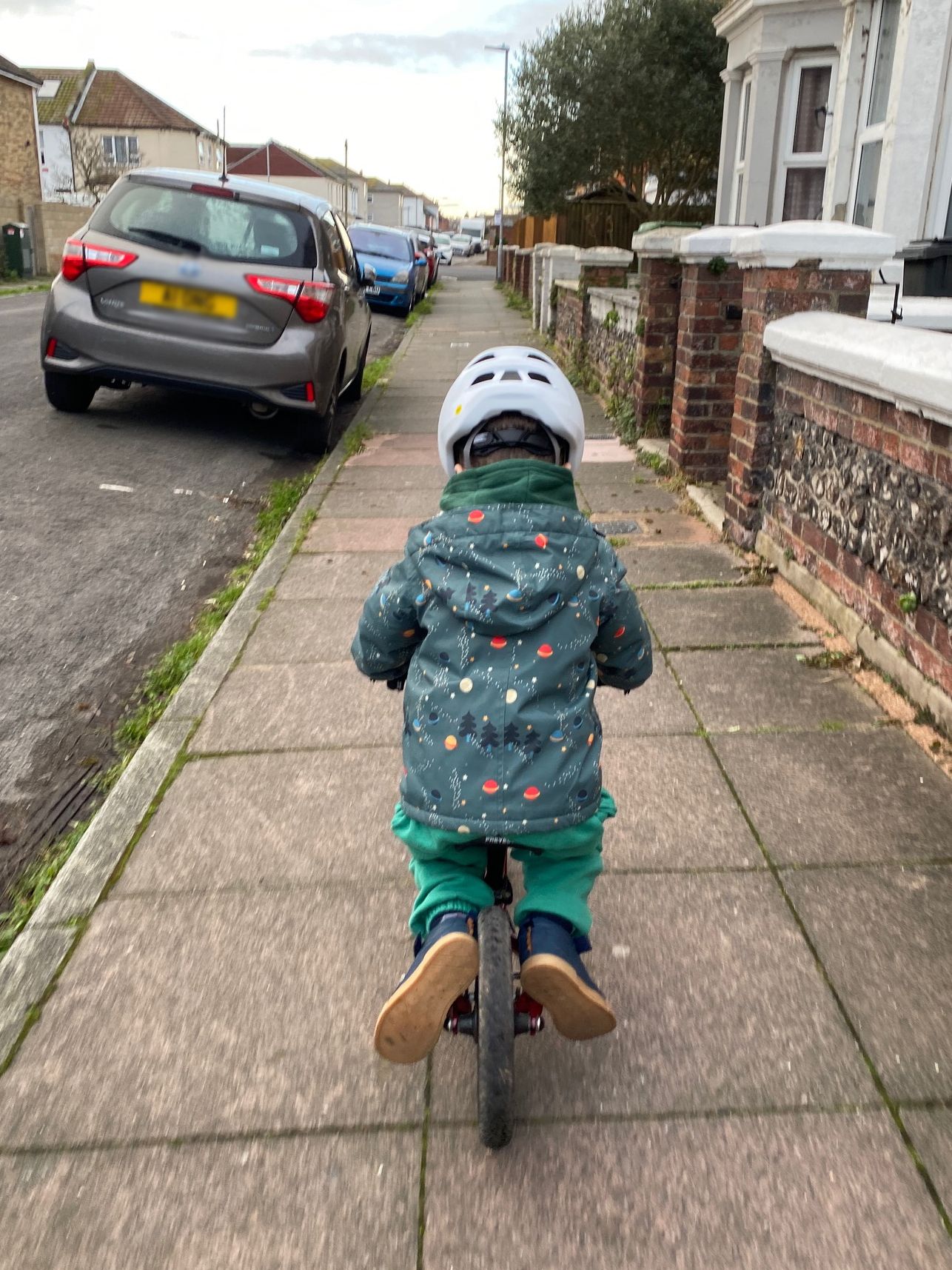 young boy using the chainstays to rest his feet on a balance bike
