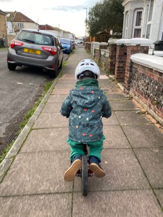 young boy using the chainstays to rest his feet on a balance bike