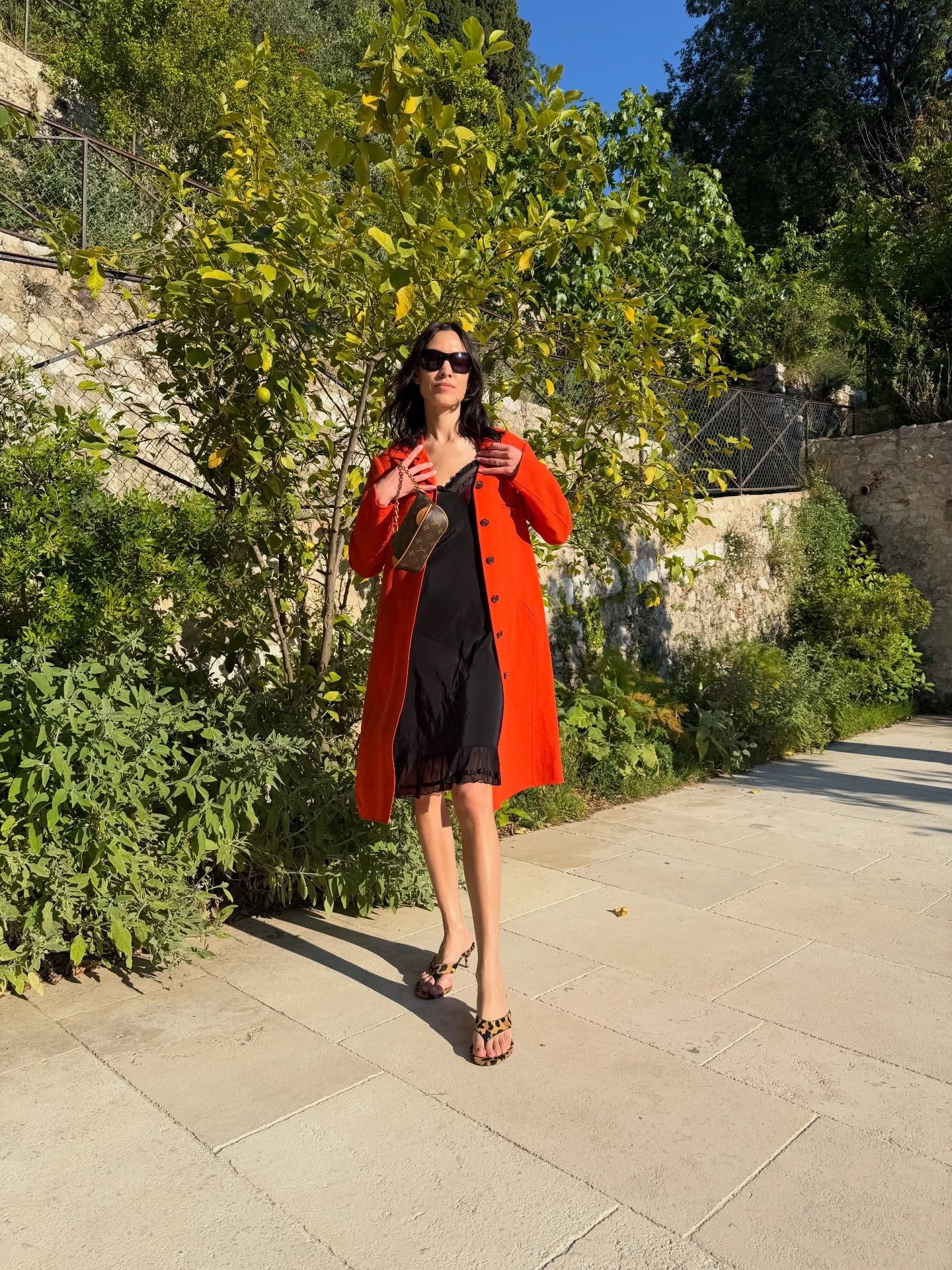 Alexa Chung wore a red trench with a black slip dress, Louis Vuitton bag, and leopard-print Alaïa thong high-heeled sandals in France.