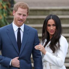 Britain's Prince Harry stands with his fiancée US actress Meghan Markle as she shows off her engagement ring whilst they pose for a photograph in the Sunken Garden at Kensington Palace in west London on November 27, 2017, following the announcement of their engagement. - Britain's Prince Harry will marry his US actress girlfriend Meghan Markle early next year after the couple became engaged earlier this month, Clarence House announced on Monday.