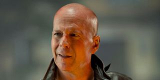 John McClane (Bruce Willis) smiles while wearing a leather jacket in A Good Day to Die Hard