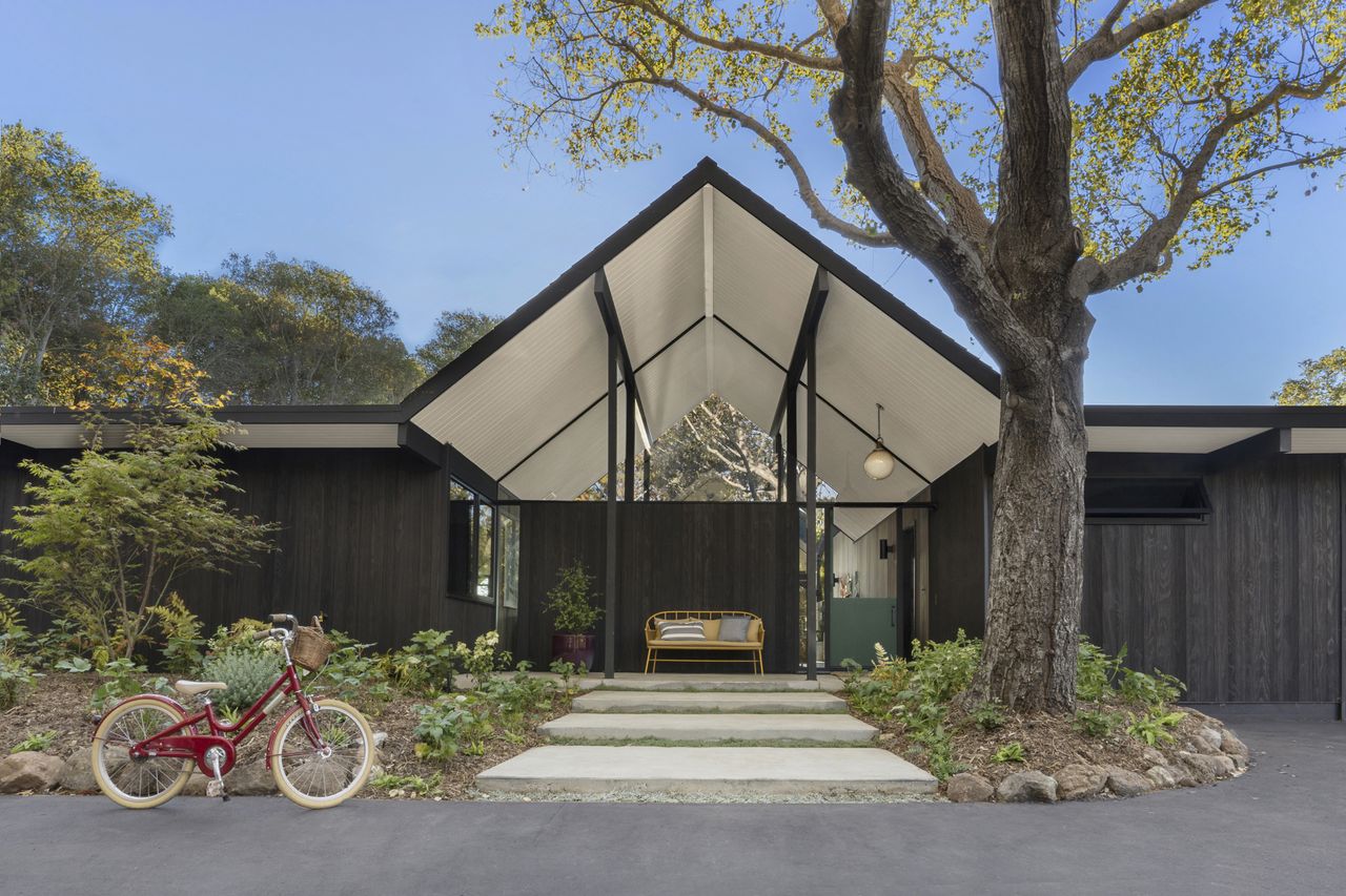 Exterior of the house with black walls and a red bike outside