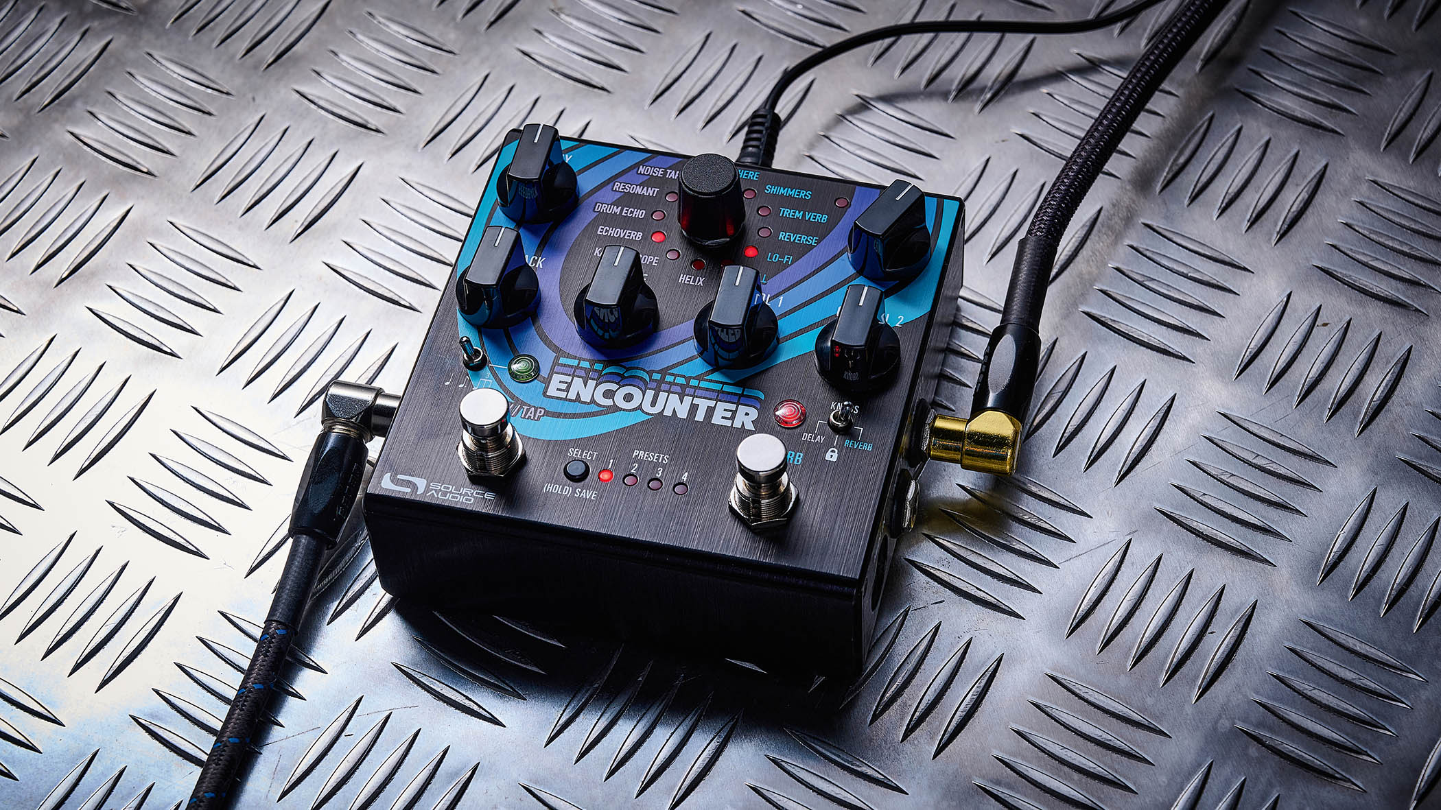 The Source Audio Encounter delay and reverb pedal is photographed here in close-up against an industrial metal background.