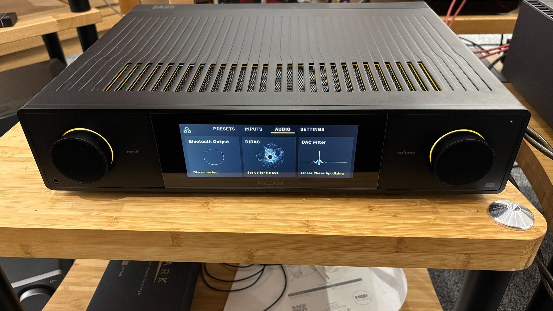 Arcam SA35 music streamer on wooden hi-fi rack, with audio settings shown on display