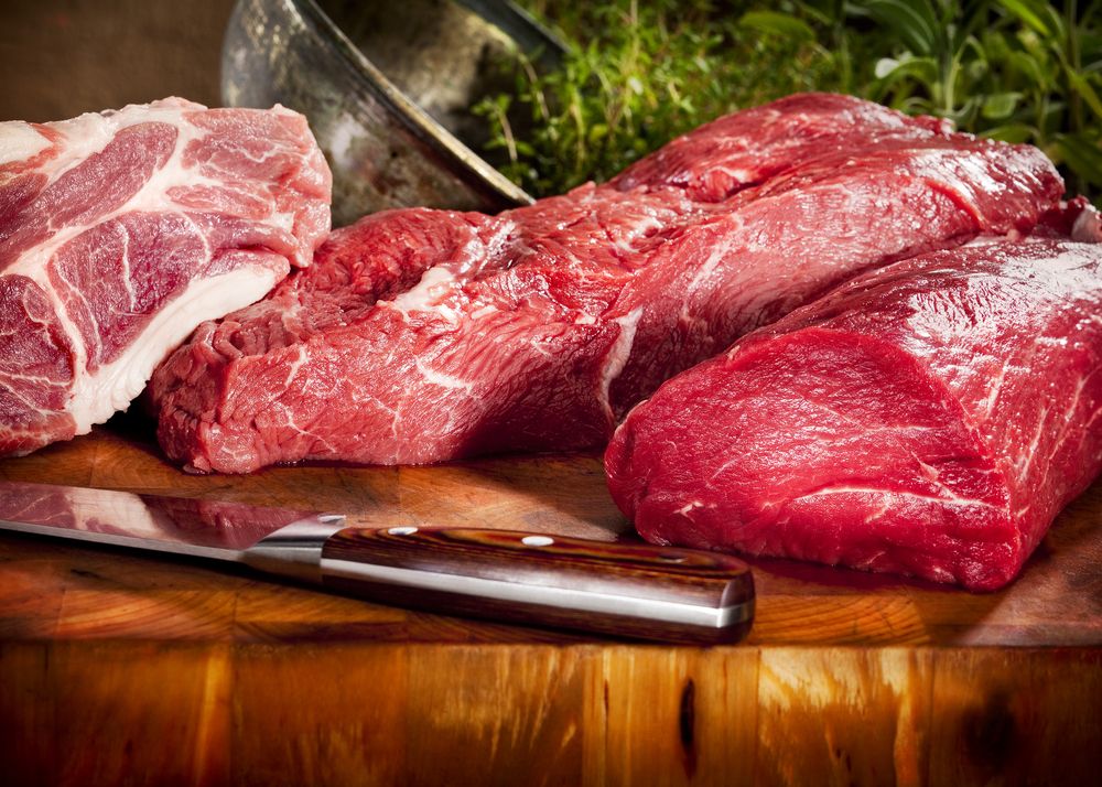 Raw meat sits on a cutting board.