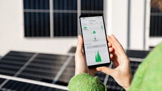 Woman monitors energy production from the solar panels with mobile phone