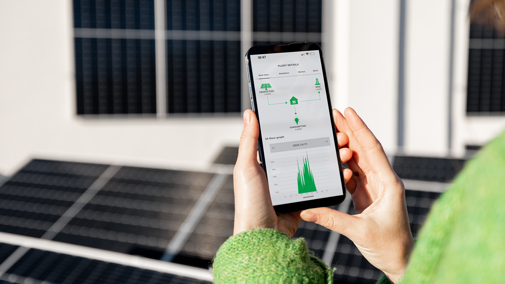 Woman monitors the energy production of the solar panels with a mobile phone