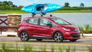 Red Chevrolet Bolt EV driving on a road