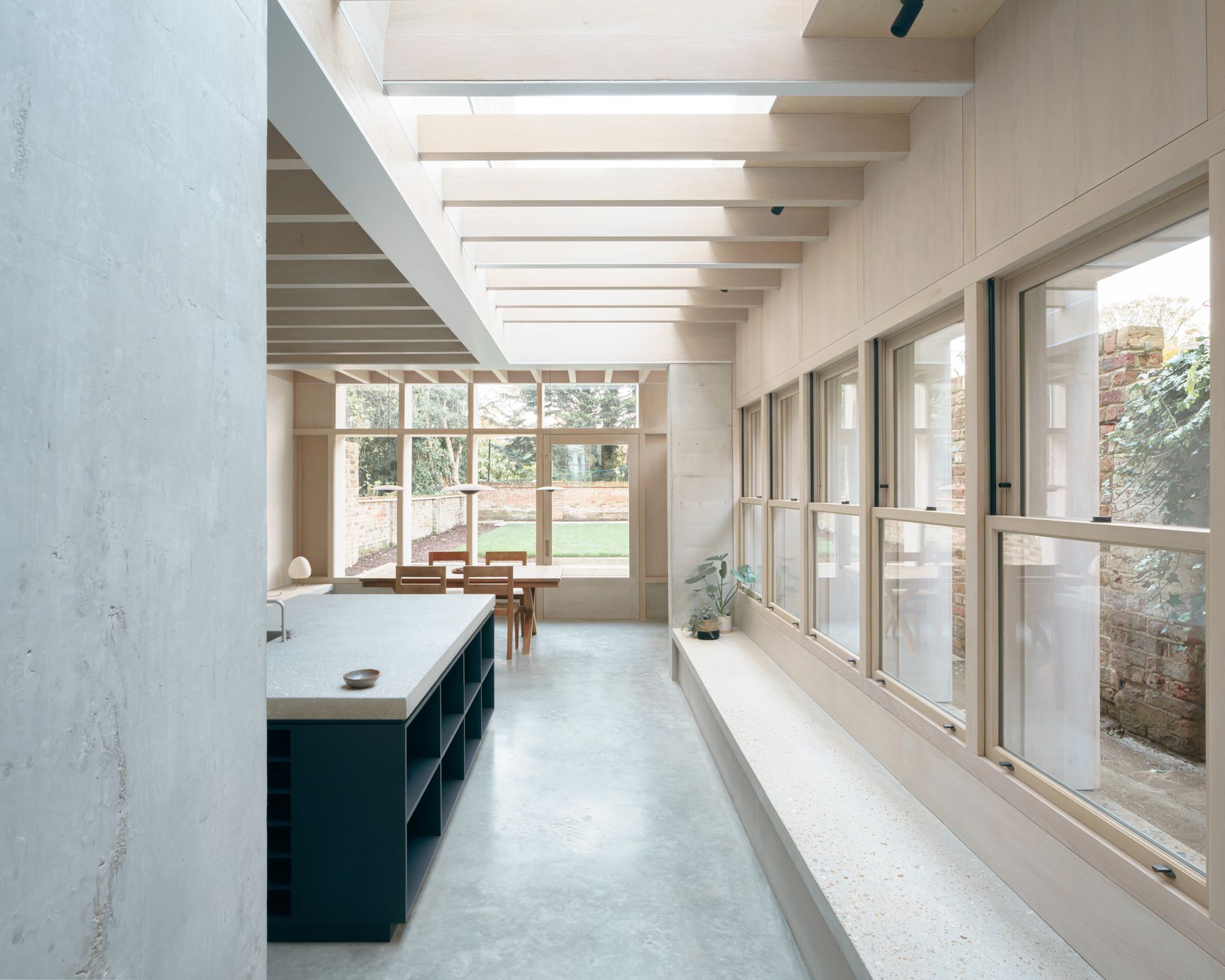 View of kitchen extension into the garden at Concrete Plinth House by DGN studio
