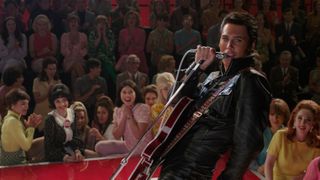 A still from the movie Elvis showing Austin Butler as Elvis singing on stage.