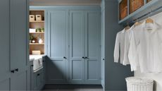 Blue laundry room, hanging shits, wooden shelves 