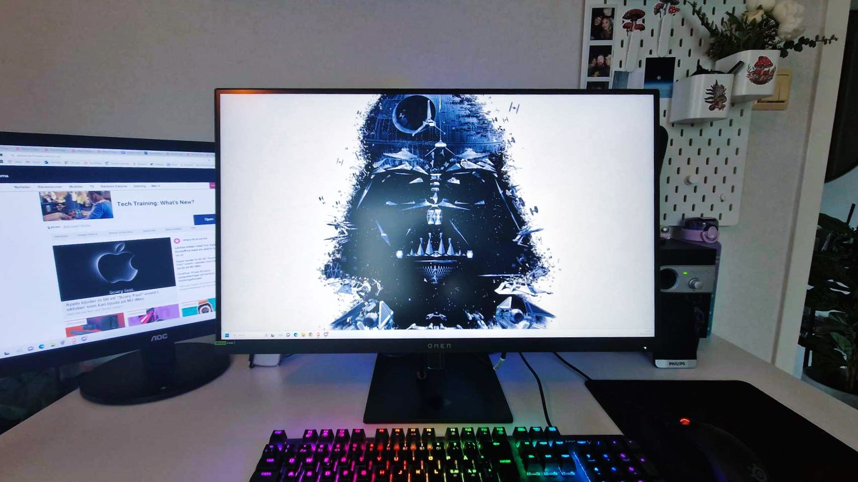 En HP Omen 27K står på ett vitt skrivbord och visar datorns hemskärm.