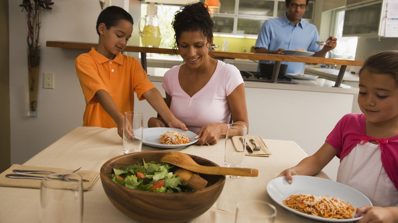 Family sitting around table with plates of pasta