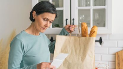 Woman worried while looking at receipt from grocery store