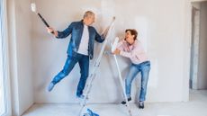 A couple painting walls and renovating their home