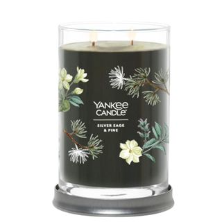 A green Yankee Candle with pine leaf and flower illustrations that says 'Yankee Candle silver sage and pine'