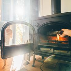 Hand adding wood to a log burning stove