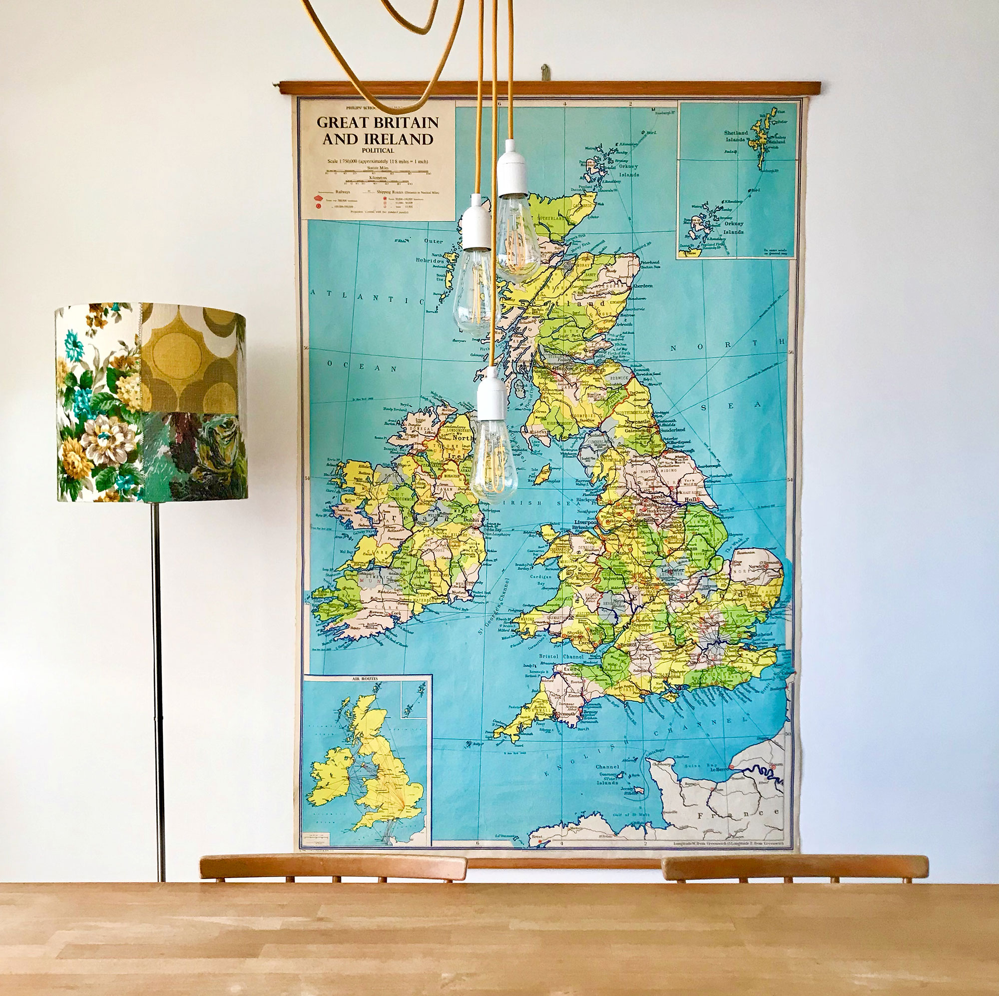 Vintage map of Great Britain and Ireland hung up on wall behind wooden table