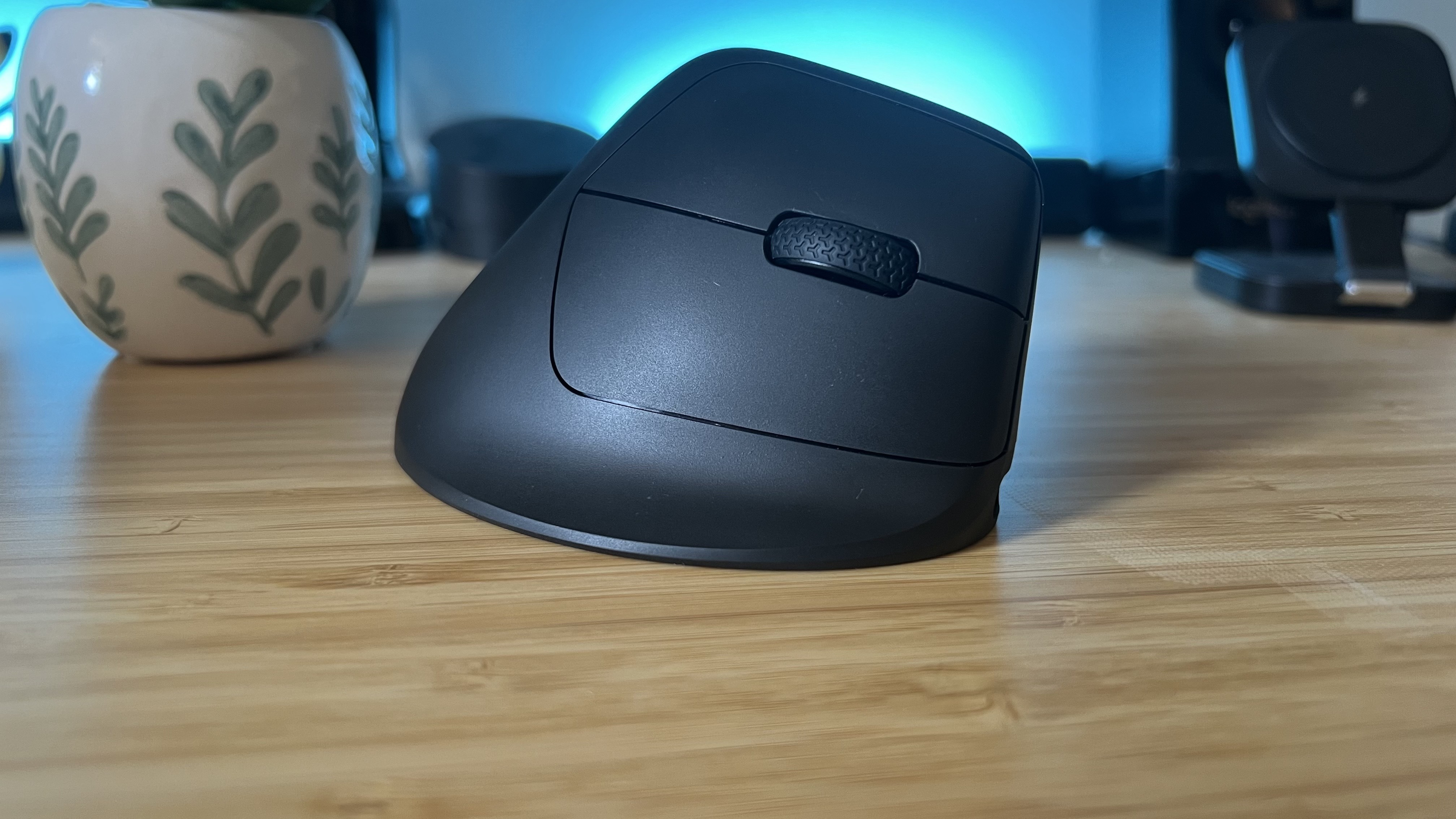 Keychron M5 vertical gaming mouse on a wooden table with blue lighting in the background