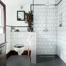 white tiled shower area with black floor tiles