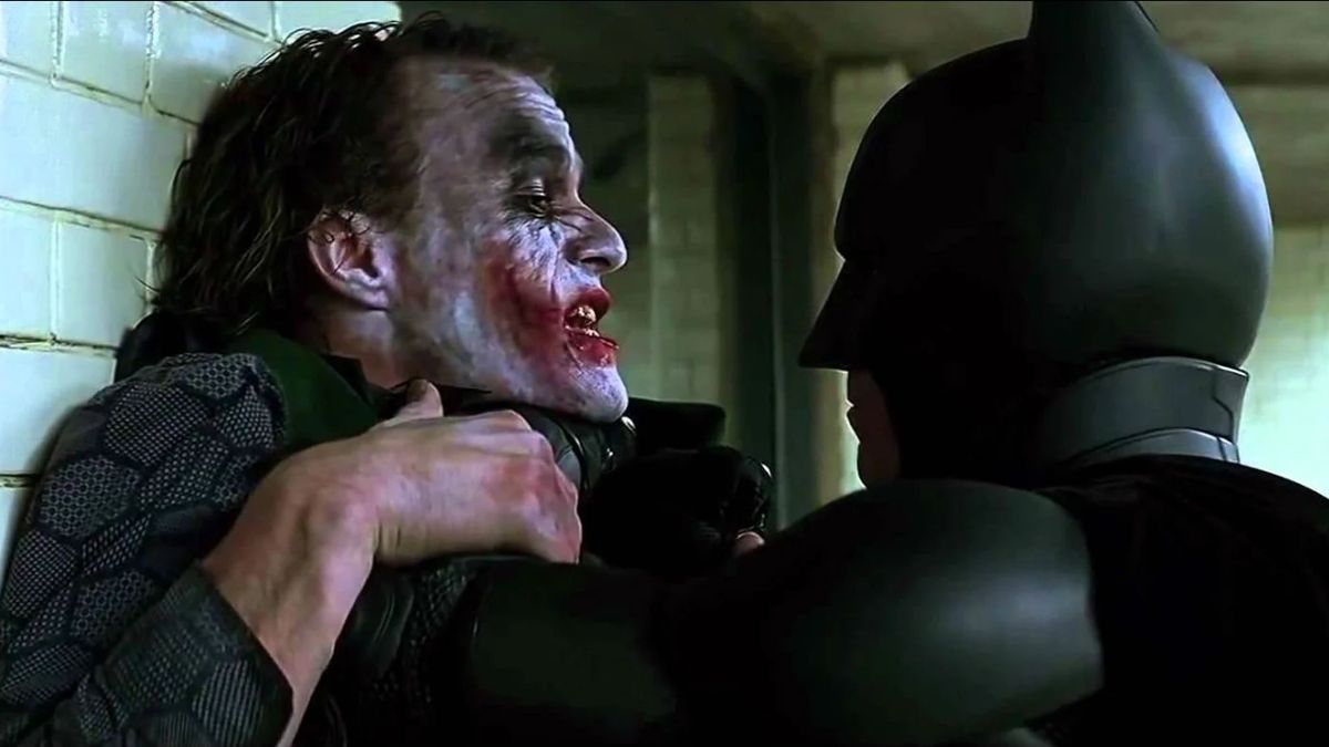 Heath Ledger as The Joker being put up against a wall by Christian Bale as Batman in The Dark Knight