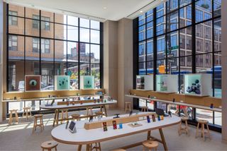 A wider view of the store's interiors, with wide windows overlooking the street and simple wooden furniture and boxes showing Google's products