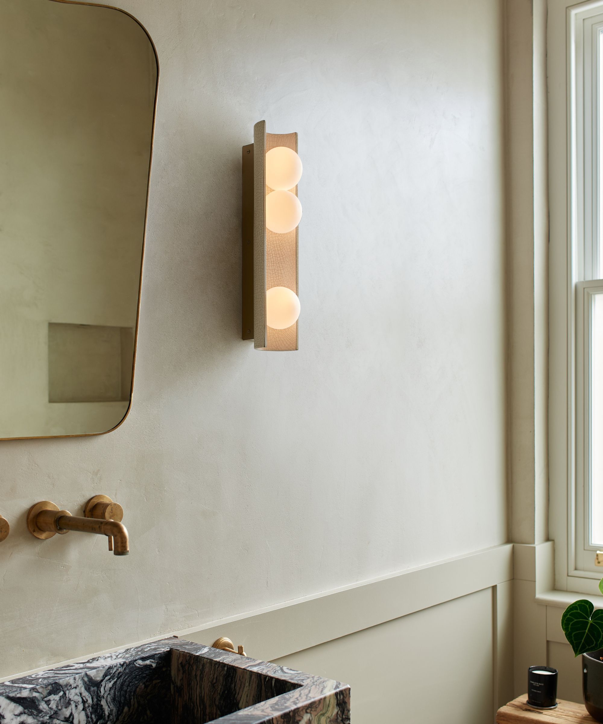 A modern bathroom wall light next to a bathroom mirror.