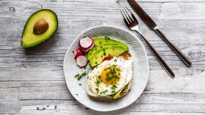 Toast with with fried egg, avocado, red radish, tomato and cress