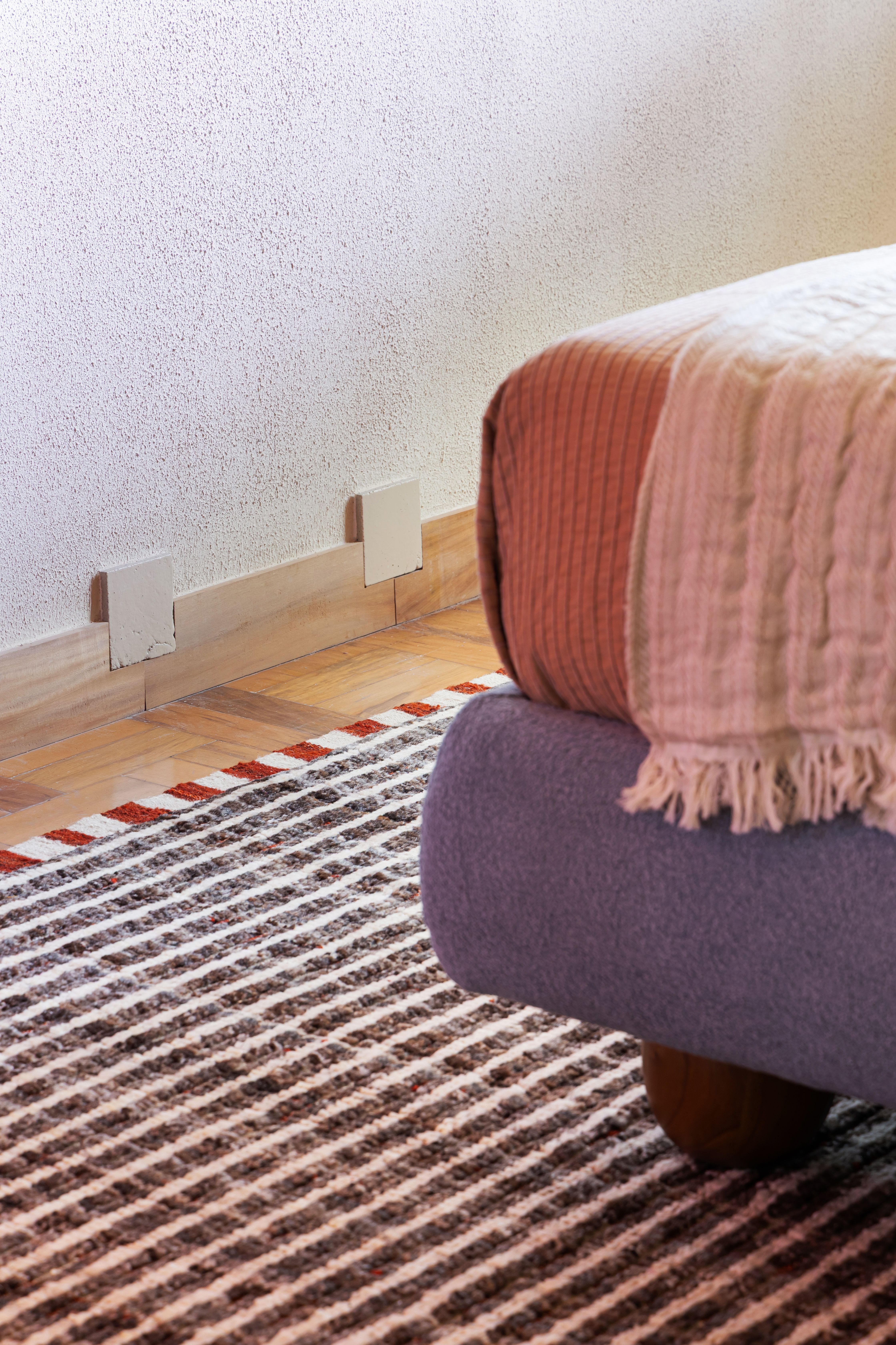 close up of baseboard, rug and bed linen