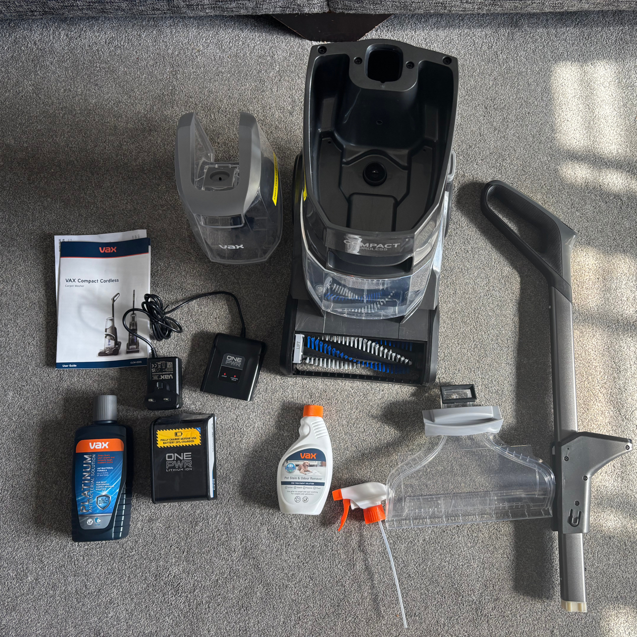 Flat lay of VAX Compact Cordless Carpet Washer and the accessories and parts included