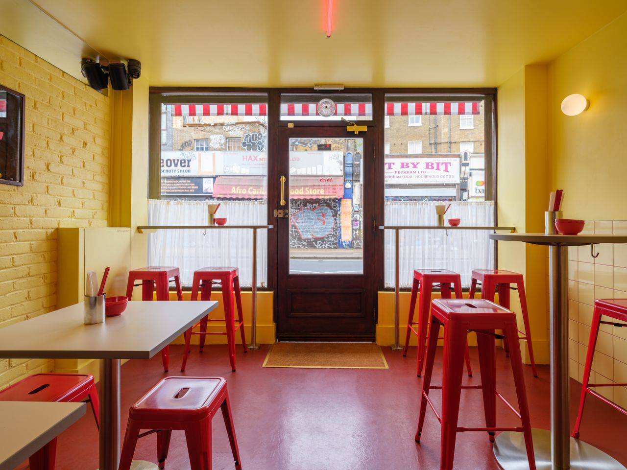 A creatively designed restaurants blends buttery walls with bold accents like lacquered red chairs and floors, porthole-like ceiling lights, spherical sconces, and chrome decor.