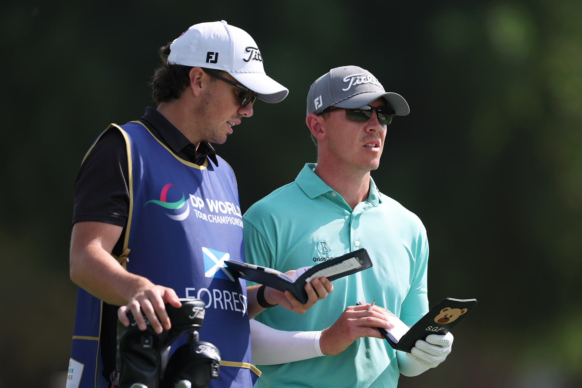 Grant Forrest talking with his caddie while studying course guides before hitting a shot on a DP World Tour event