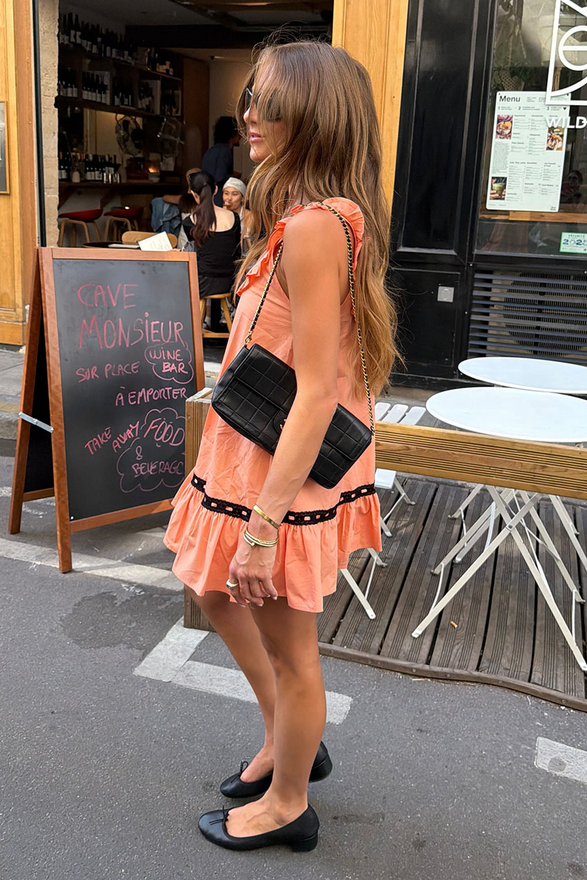 A woman wearing a pink dress, and black heels.