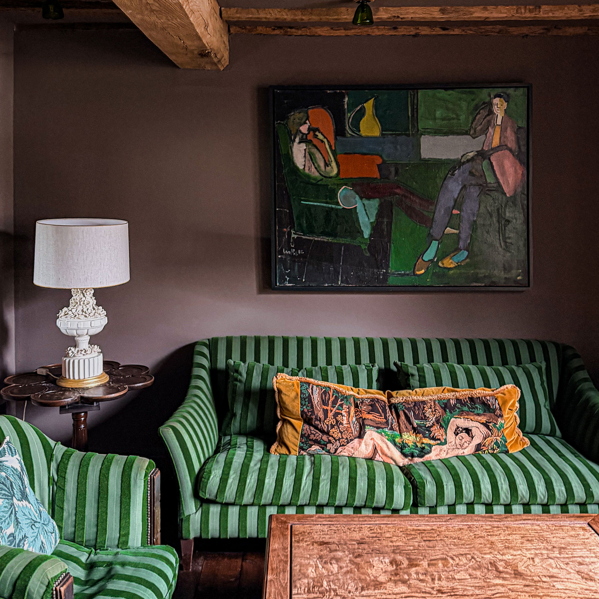 Purple living room with wooden coffee table amd matching armchair and sofa in two toned green stripe upholstery