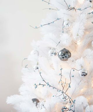 white christmas tree branches with metallic ornaments
