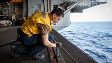 A sailor performing routine maintenance on a US Navy aircraft carrier