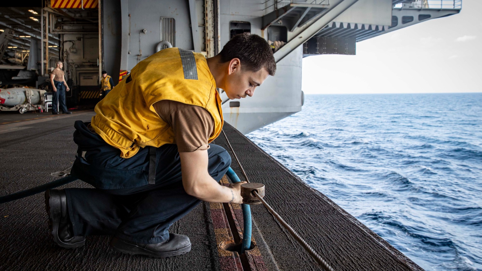 A sailor performing routine maintenance on a US Navy aircraft carrier